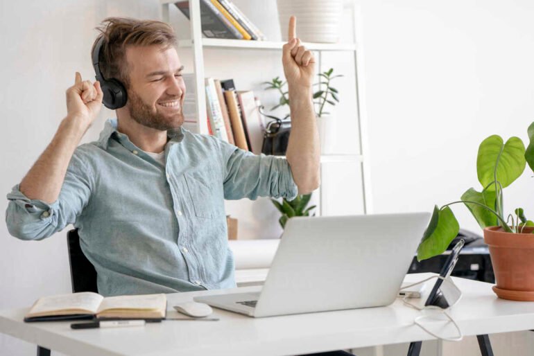 Excited man listening to music at desk in office